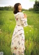 A woman standing in a field holding a flower.