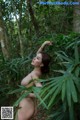 A naked woman standing in the middle of a forest.