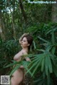 A naked woman standing in the middle of a forest.