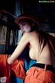 A woman in an orange uniform is sitting on a bus.