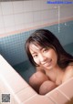 A young woman sitting in a bathtub smiling at the camera.