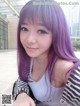 A woman with purple hair is posing for a picture.