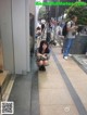 A woman crouching down in front of a camera on a tripod.