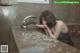 A woman is washing her hands in the bathroom sink.