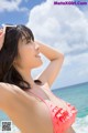 A woman in a pink bikini standing on the beach.