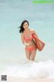 A woman in a bikini holding a surfboard in the ocean.