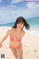 A woman in a pink bikini running on the beach.