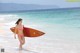 A woman in a bikini holding a surfboard on the beach.