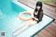 A woman sitting on the edge of a swimming pool with an inflatable ring.