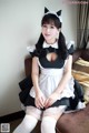 A woman dressed as a maid sitting on a couch.