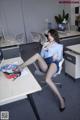 A woman sitting at a desk in an office with her legs crossed.