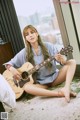 A woman sitting on the floor playing a guitar.