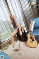 A woman sitting on a chair next to a guitar.