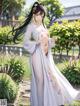 A woman in a white kimono standing in a garden.