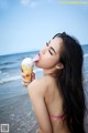 A woman in a bikini eating an ice cream cone.