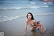 A woman in a bikini sitting in the water.