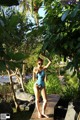 A woman in a bathing suit standing on a wooden walkway.