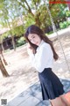 A woman in a white shirt and black skirt on a swing.