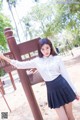 A woman in a school uniform posing in front of a sign.