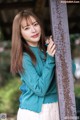 A woman leaning against a metal pole in a park.