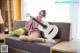 A woman sitting on a couch holding a guitar.