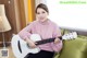 A woman sitting on a couch holding a white guitar.