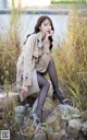 A woman sitting on a rock in a field of tall grass.