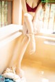 A woman in a red bra and white stockings sitting on a window sill.