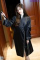 A woman wearing a black robe standing in front of a door.