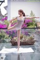 A woman in a white leotard is doing a yoga pose.