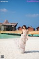 A woman in a white dress standing on a beach.